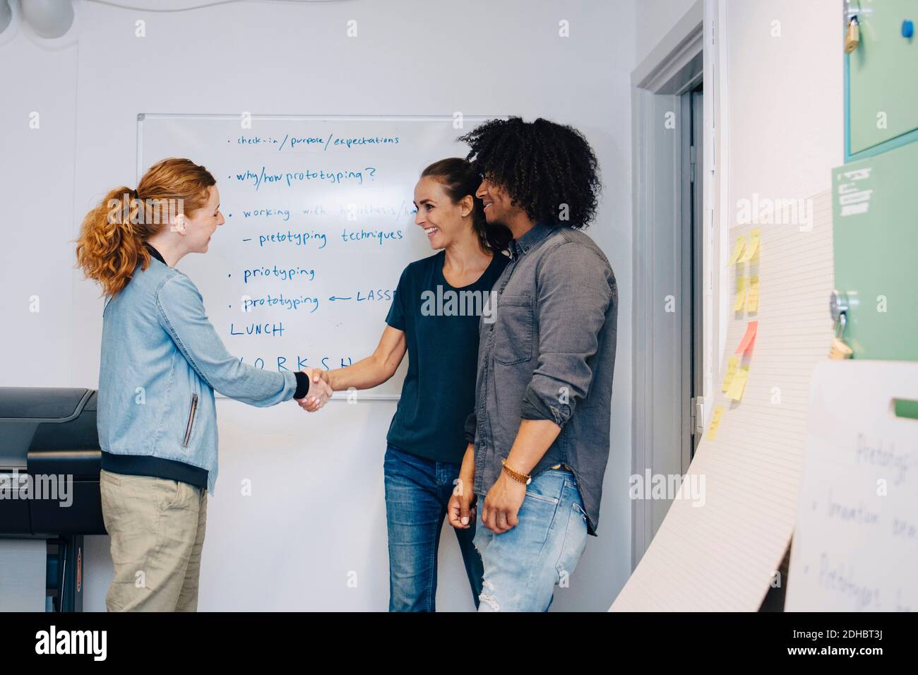 Businessman looking while standing by female colleagues greeting in creative office Stock Photo