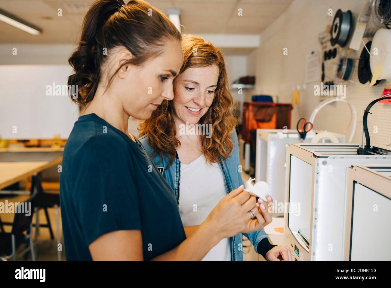 Female entrepreneurs looking at snail figurine at creative office Stock Photo