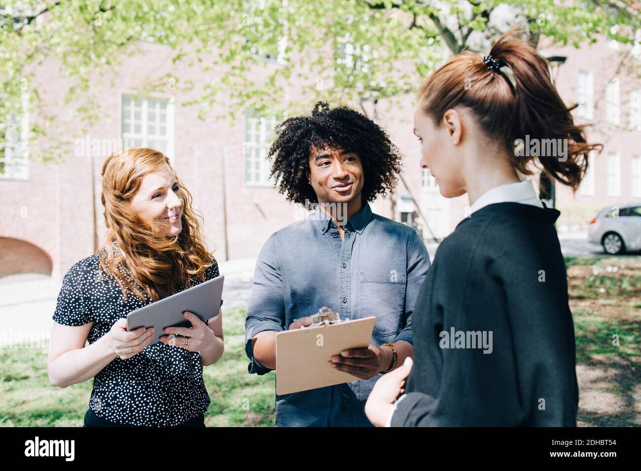 Confident businesswoman discussing with multi-ethnic colleagues while standing outdoors Stock Photo