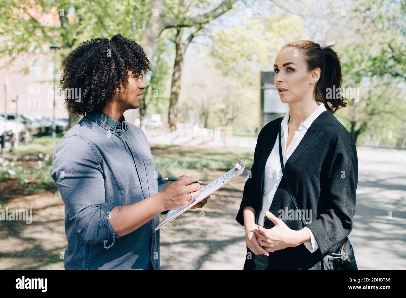 Confident businessman discussing with female colleague while standing on road Stock Photo