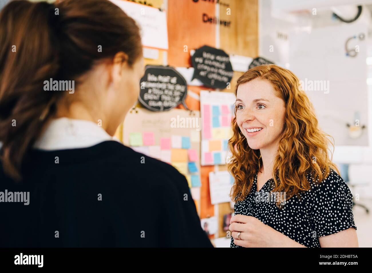 Smiling businesswoman discussing with female colleagues at creative office Stock Photo