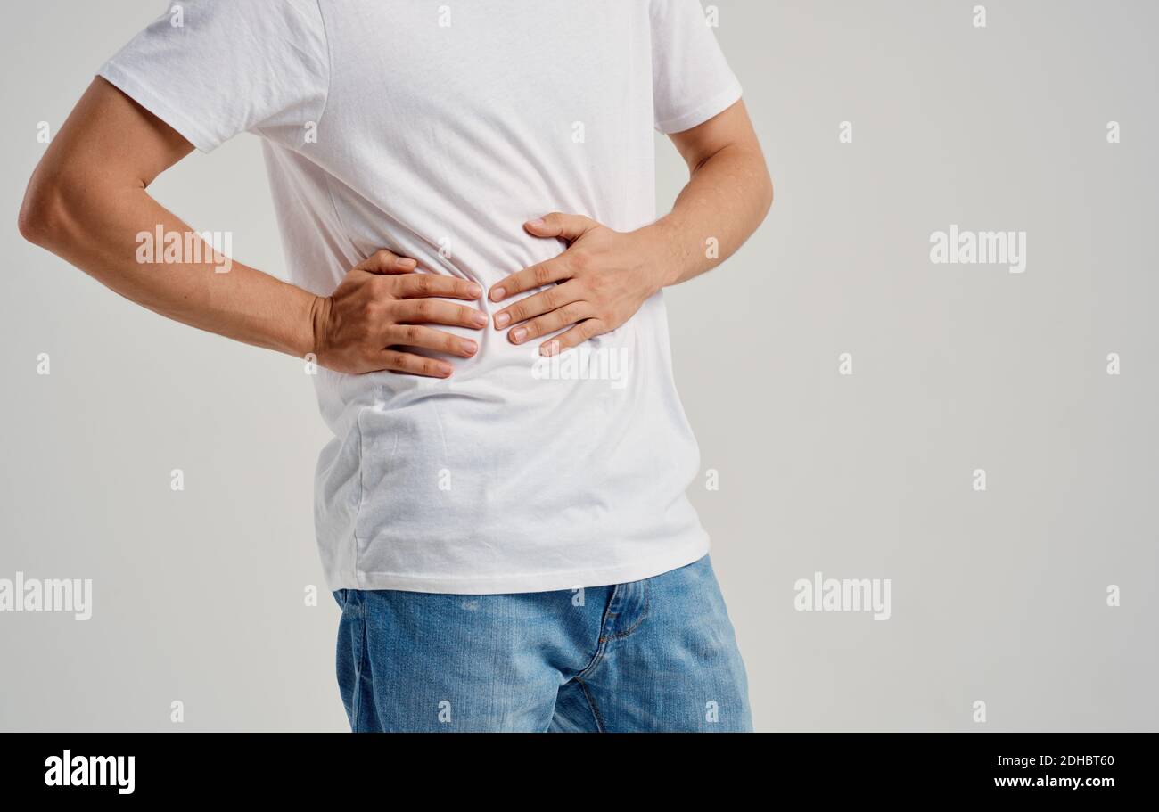 guy in a tshirt and jeans touches his hands near the abdomen pain