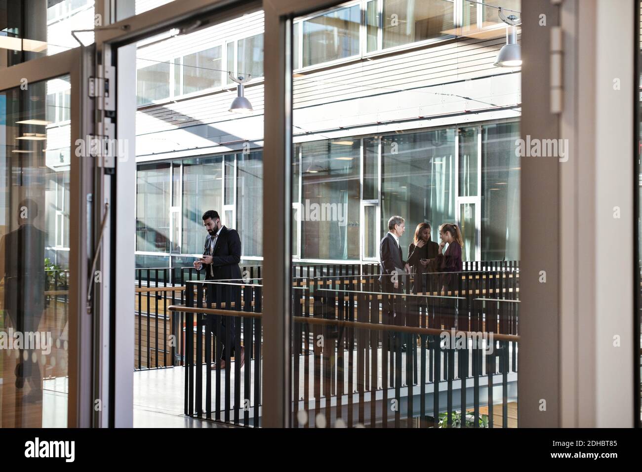 Businessman using mobile phone while colleagues discussing in background Stock Photo