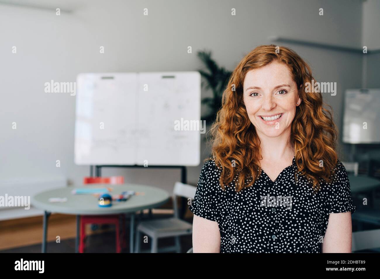 Portrait of confident redhead businesswoman standing at creative office Stock Photo