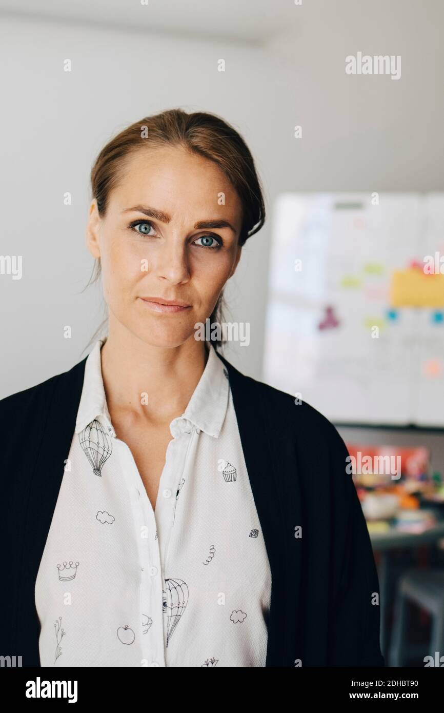 Portrait of confident mid adult businesswoman standing at creative office Stock Photo
