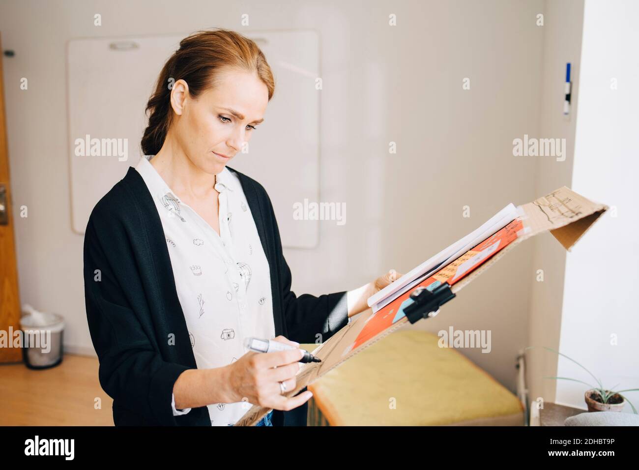 Confident businesswoman writing strategy on placard at creative office Stock Photo
