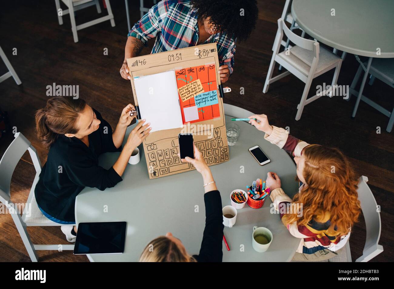 High angle view of manager photographing strategy on placard with technicians at creative office Stock Photo