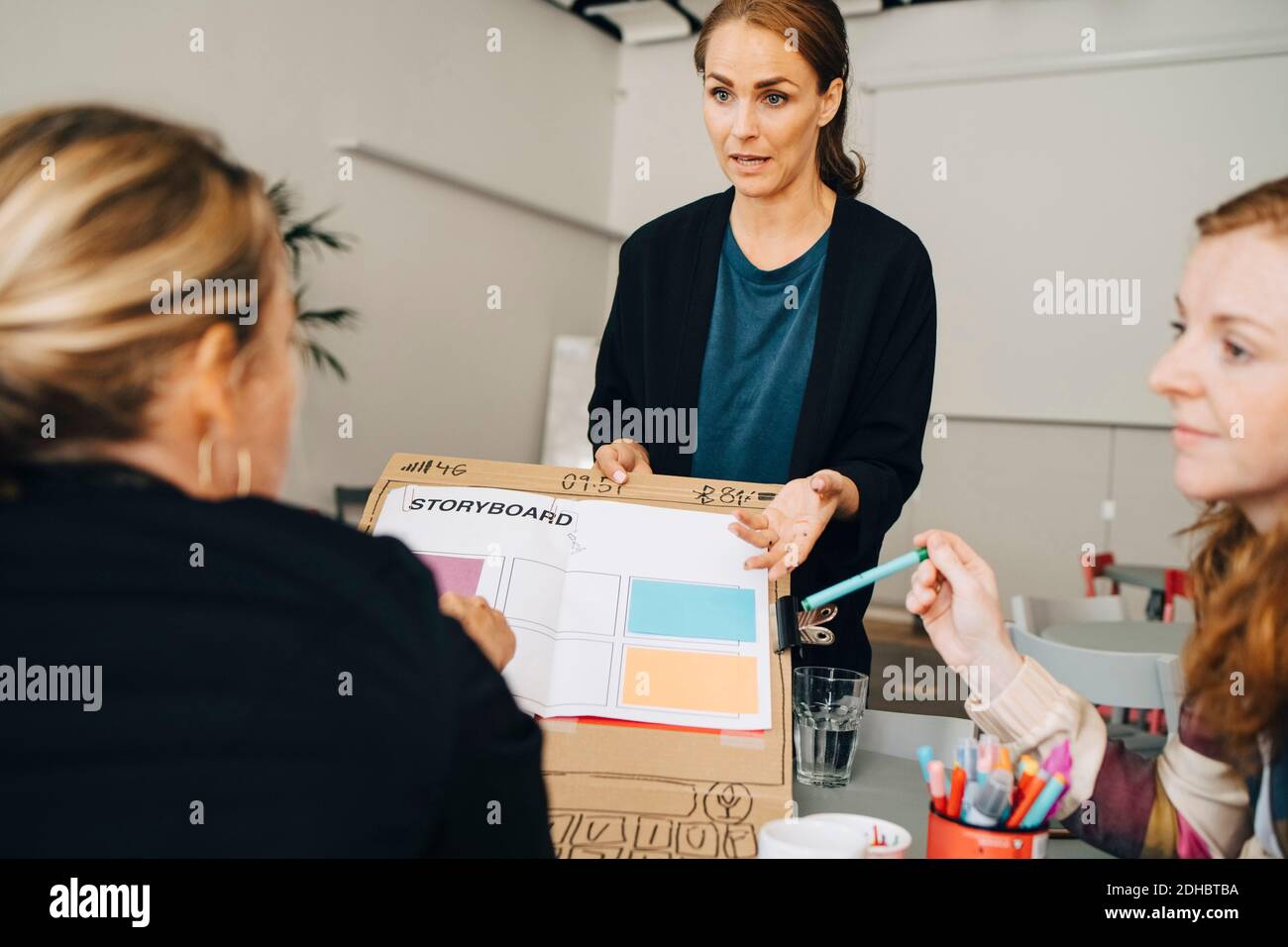 Confident female technicians explaining strategy on placard to manager at creative office Stock Photo