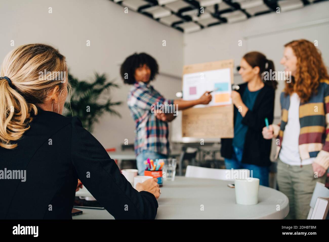 Female manager looking at confident technicians explaining strategy on placard in creative office Stock Photo