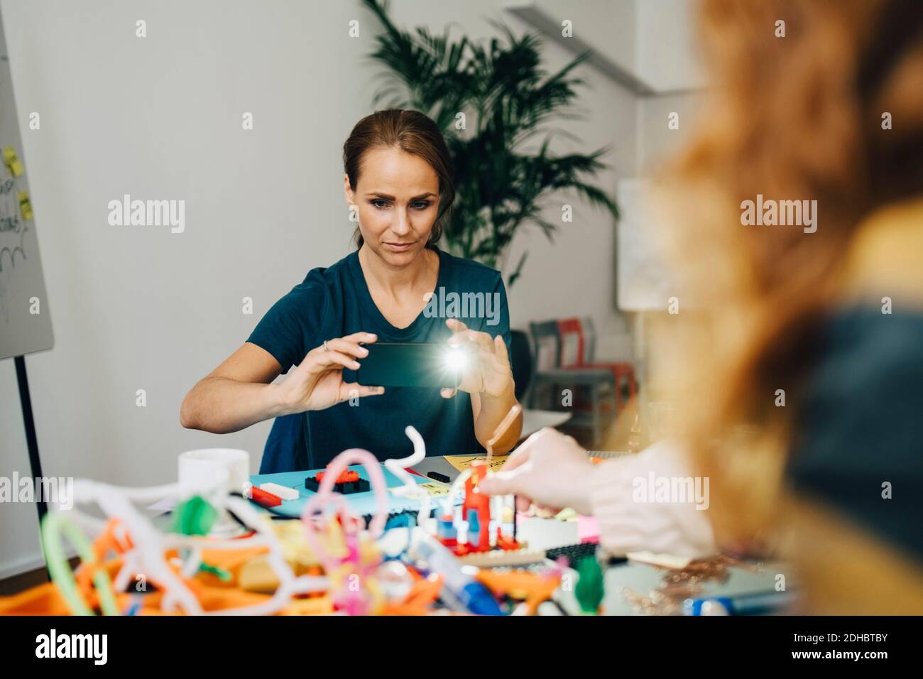 Confident businesswoman photographing stationery on table at creative office Stock Photo