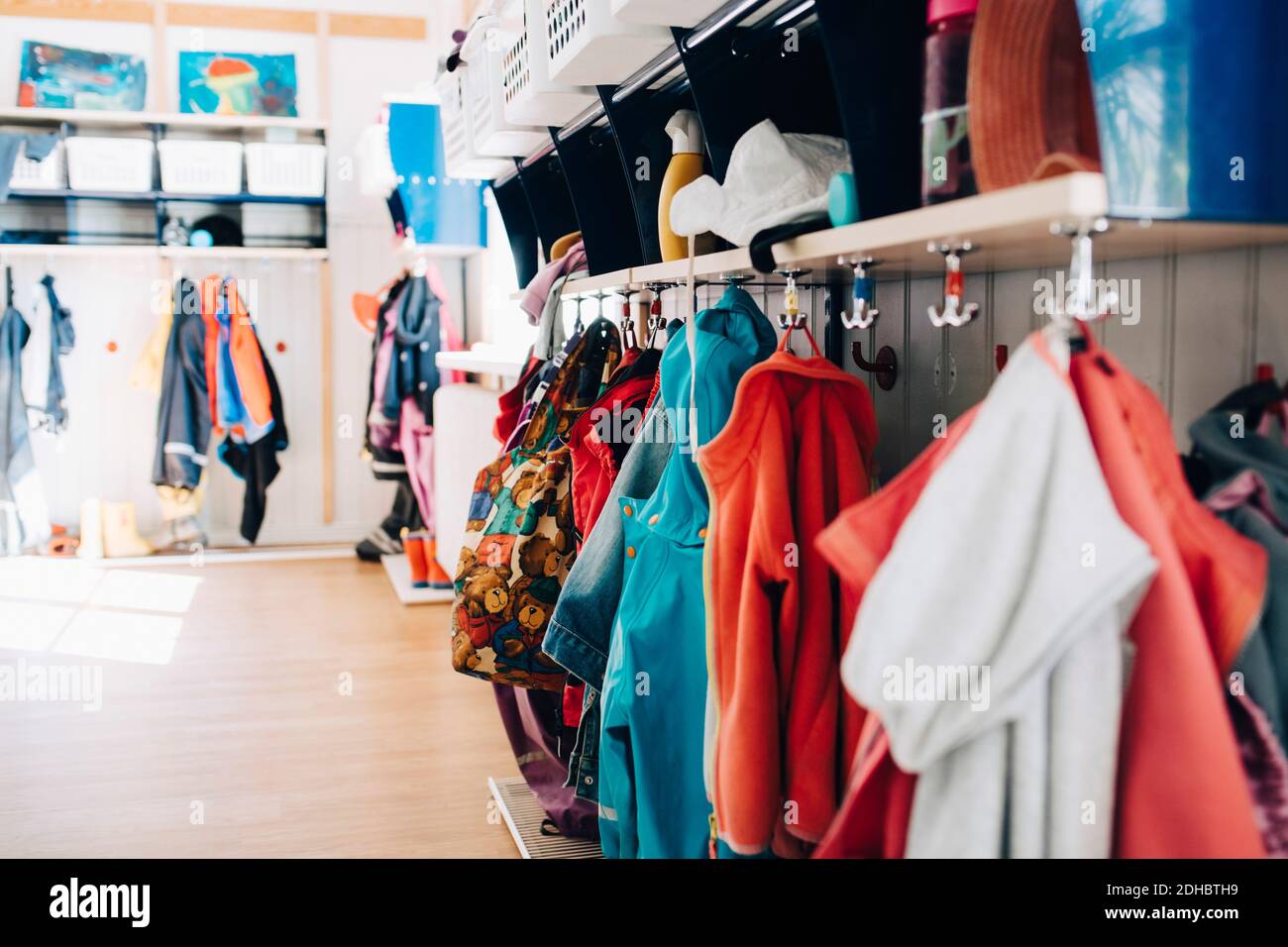 Various clothes hanging from hooks in cloakroom at preschool Stock Photo