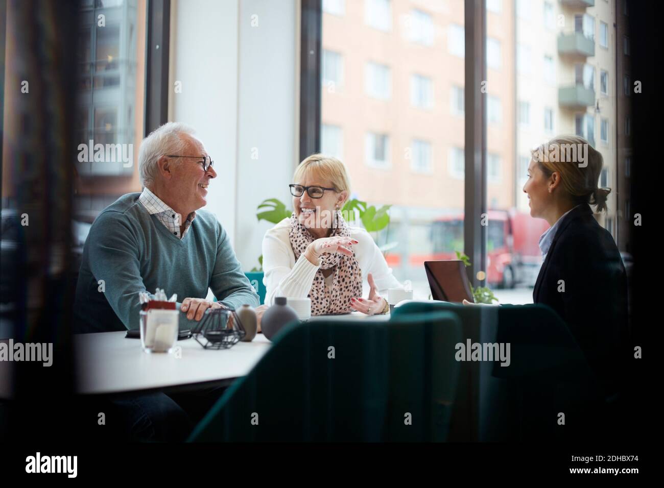 Smiling senior couple talking while sitting with realtor in office Stock Photo