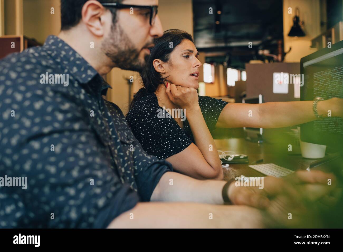 Female computer programmer with colleague discussing over coding in office Stock Photo