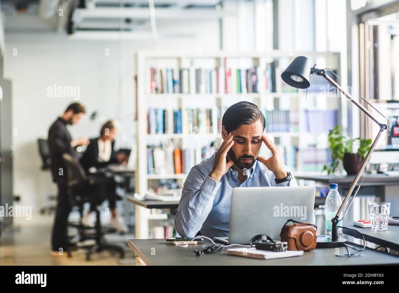 Frustrated businessman looking at laptop while sitting in office Stock ...