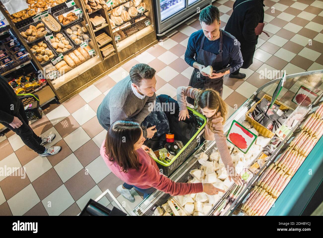 High angle view of family choosing food packets from shelf by owner in store Stock Photo