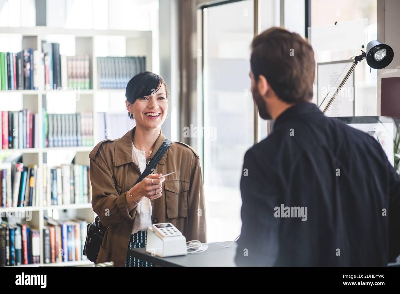 Businesswoman smiling while receiving card to male entrepreneur at counter in office Stock Photo