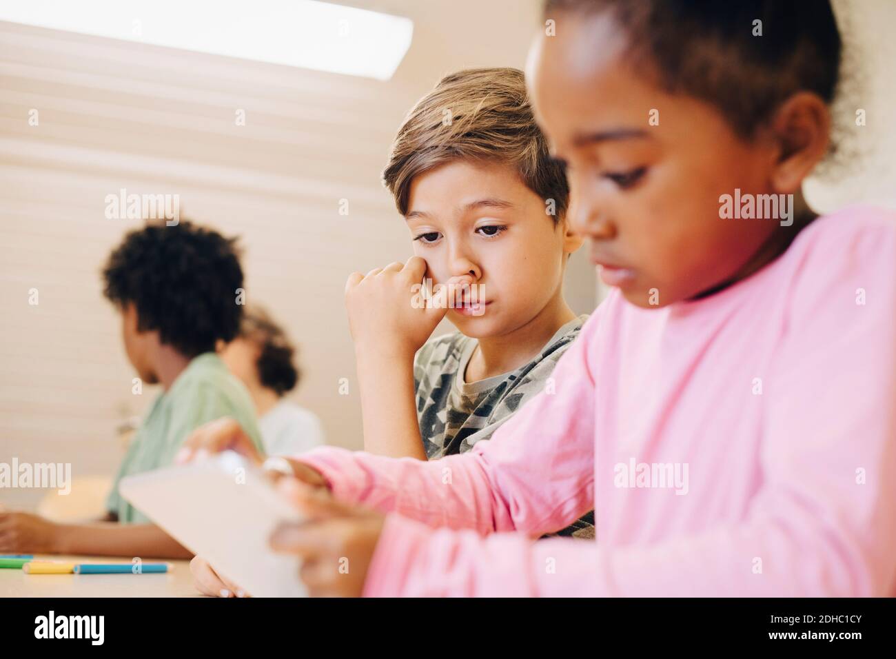 Boys using digital tablet while learning at classroom Stock Photo