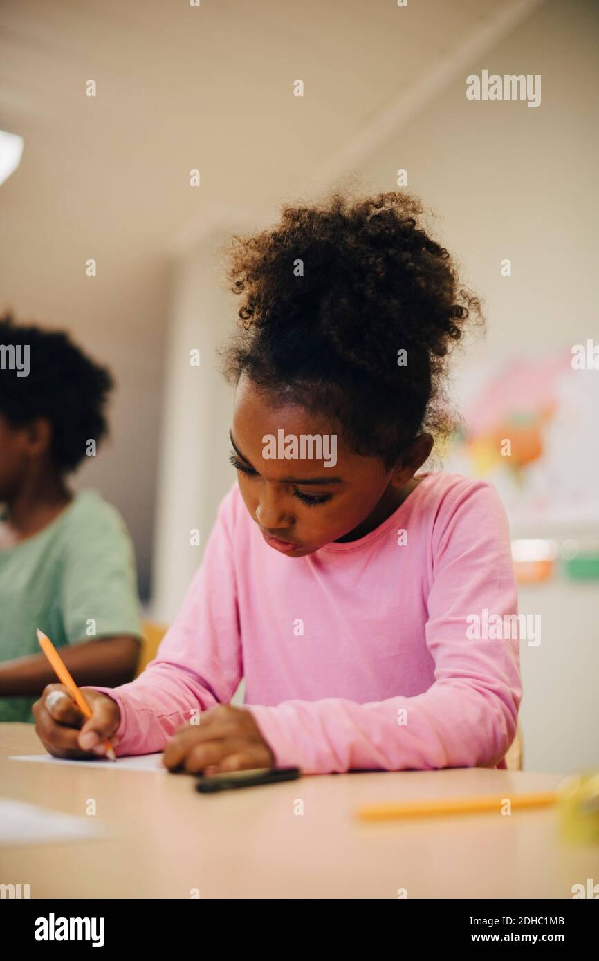 Boy writing at desk in elementary classroom Stock Photo