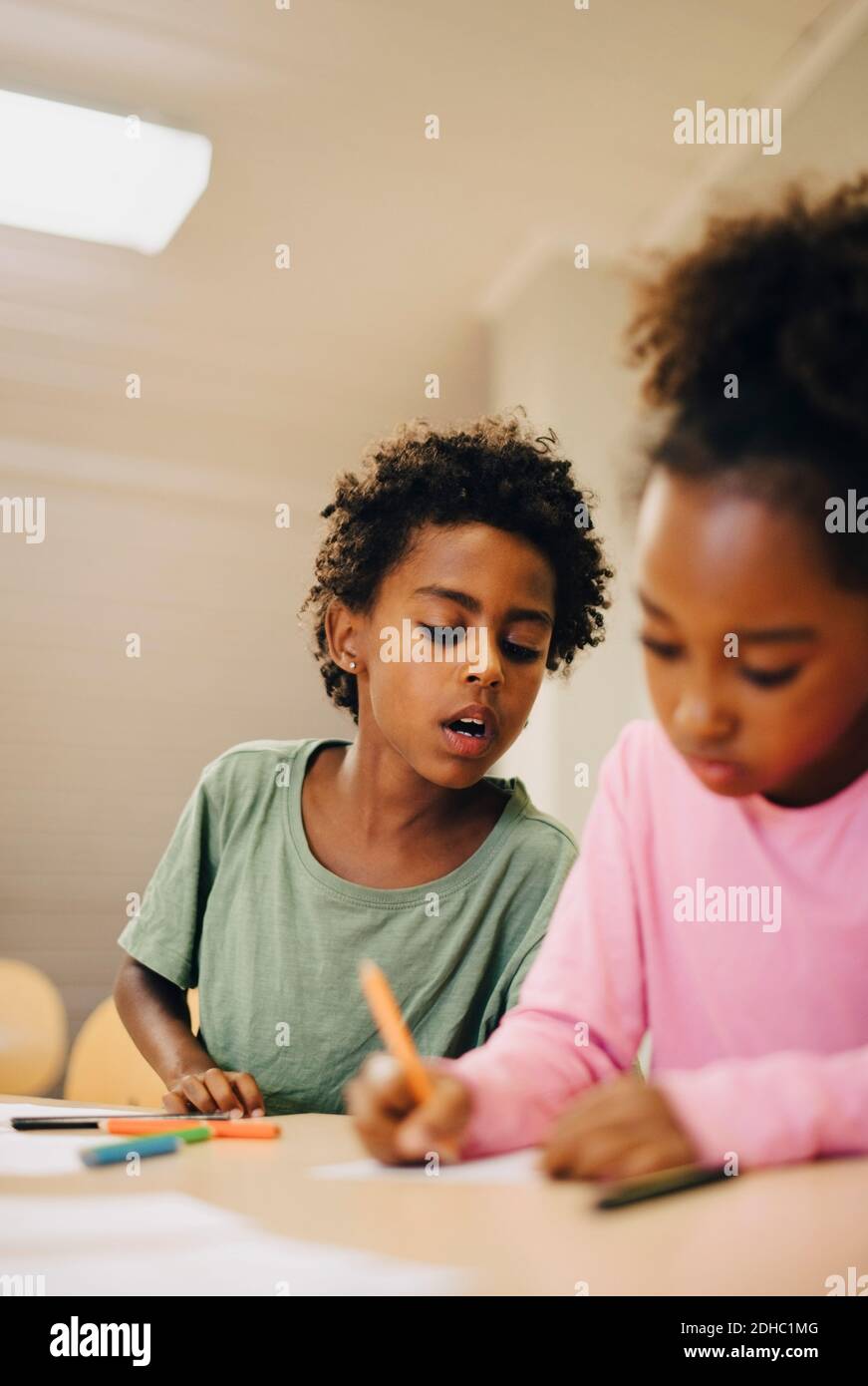 Schoolboys writing at desk in classroom Stock Photo