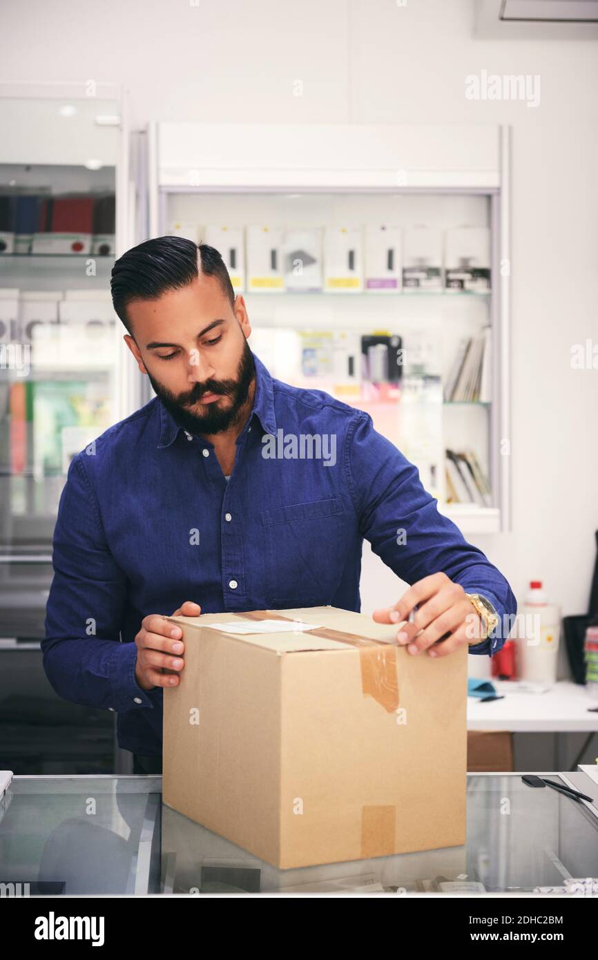 Male owner packing box at counter in electronics store Stock Photo