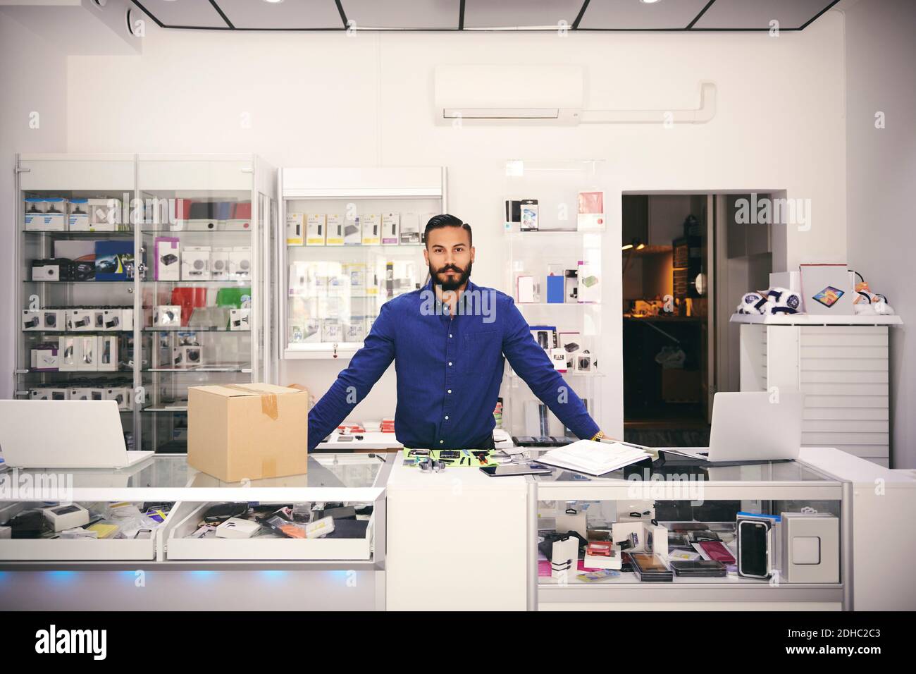Portrait of confident owner standing at counter in electronics store Stock Photo