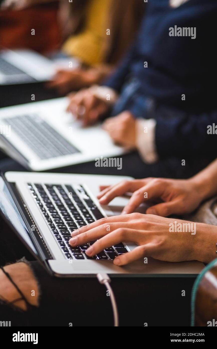 Midsection of colleagues using laptops in creative office Stock Photo