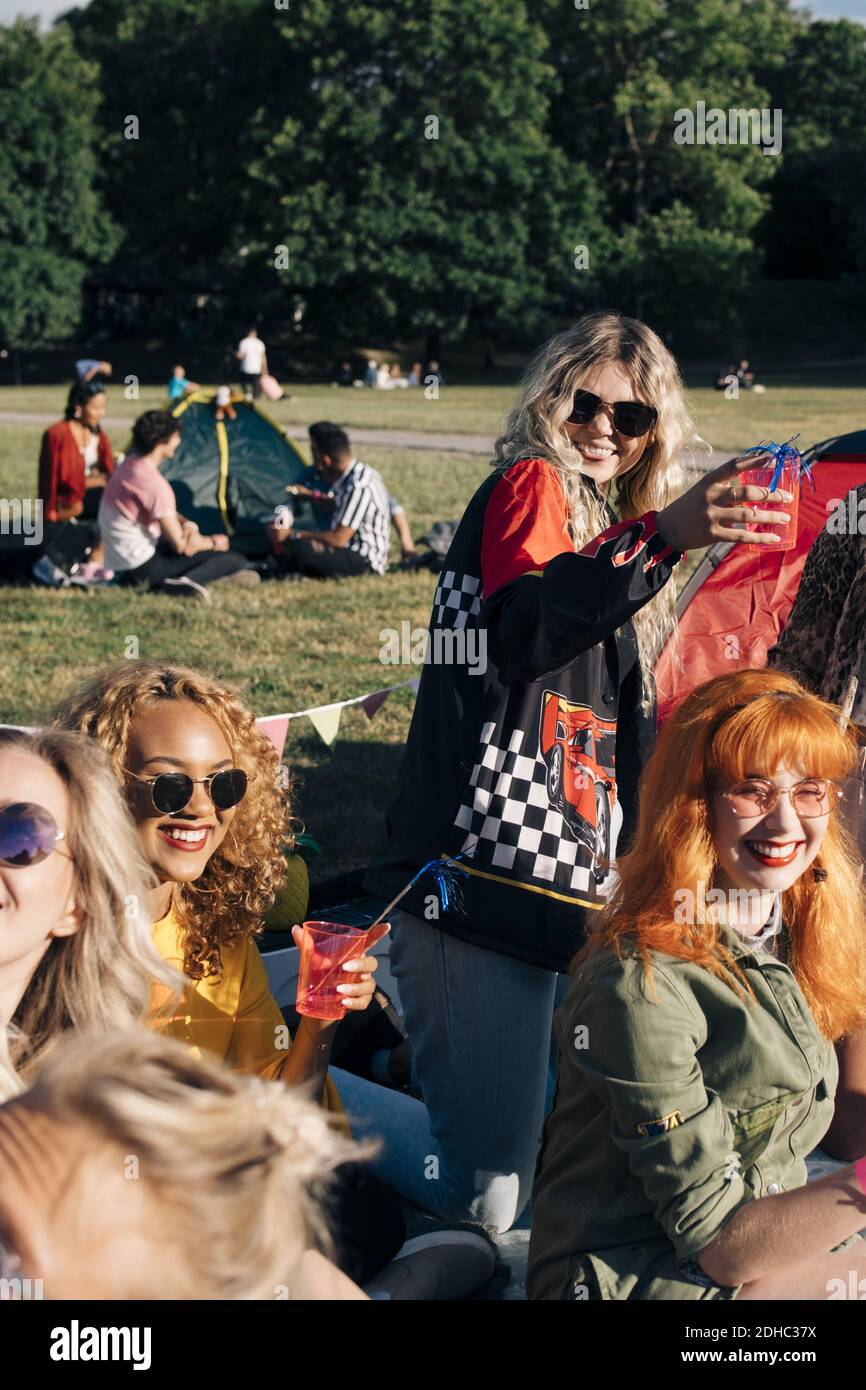 Smiling friends enjoying drink while camping on sunny day in concert Stock Photo