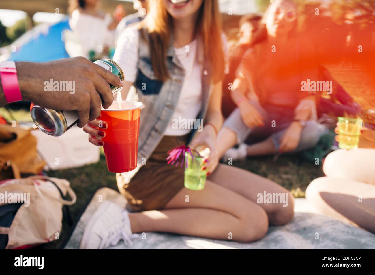 Cropped image of man pouring alcohol in friend's glass at party in festival Stock Photo