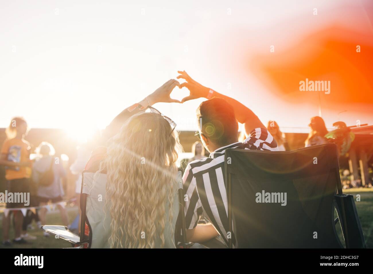 Rear view of couple making heart shape while enjoying in music festival ...