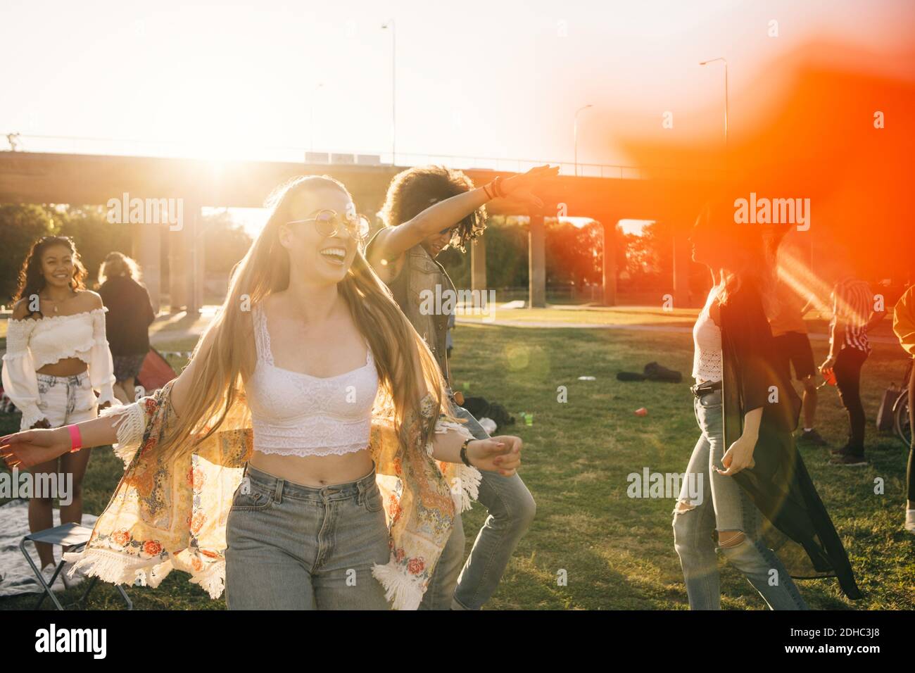 Happy young woman dancing with friends on sunny day in music event Stock Photo