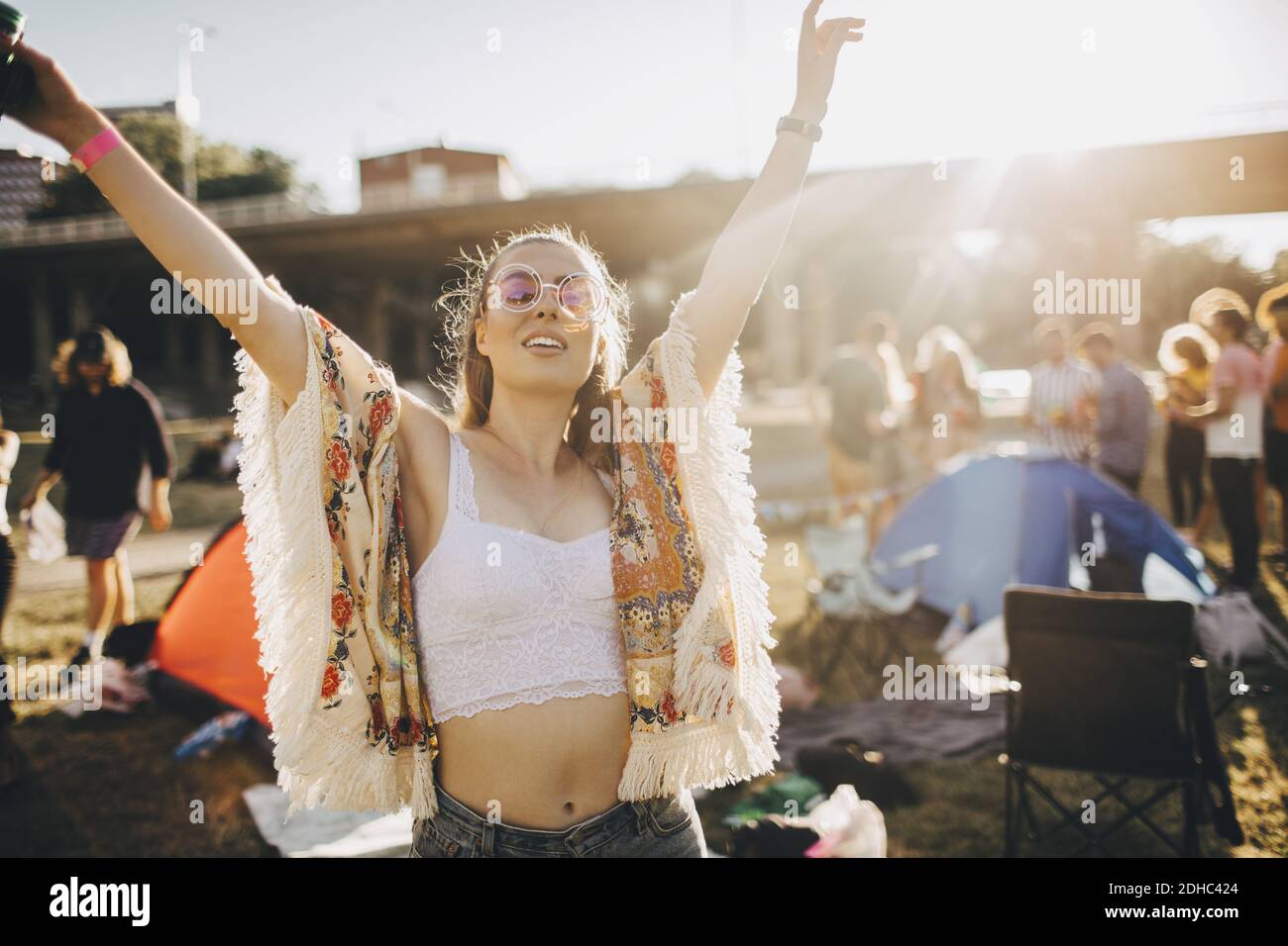 Happy young woman with arms raised enjoying at music event during summer Stock Photo
