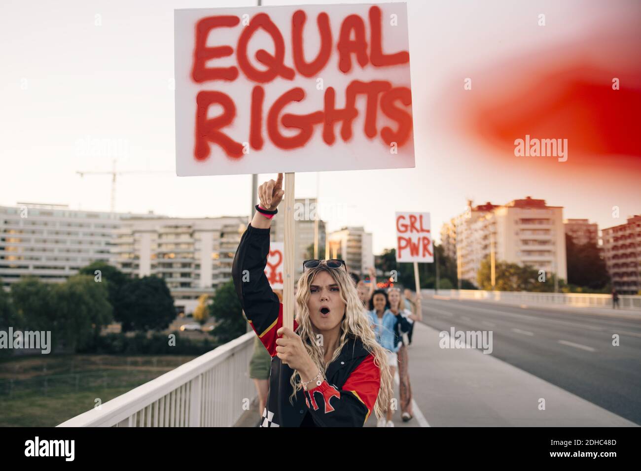 Women with poster shouting while marching for equal rights on bridge in city Stock Photo
