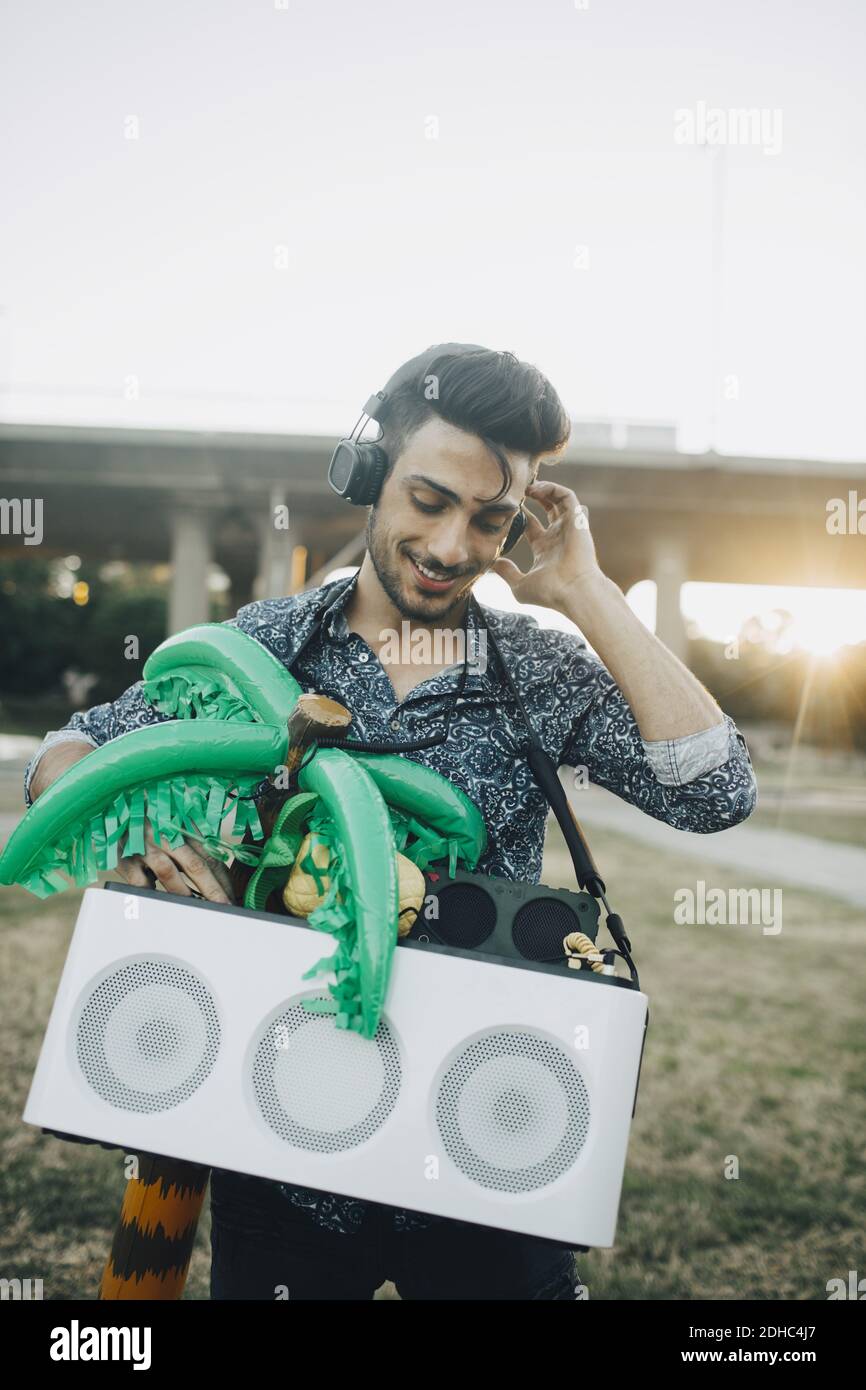 Smiling young man with speaker and palm tree balloon enjoying music in festival Stock Photo