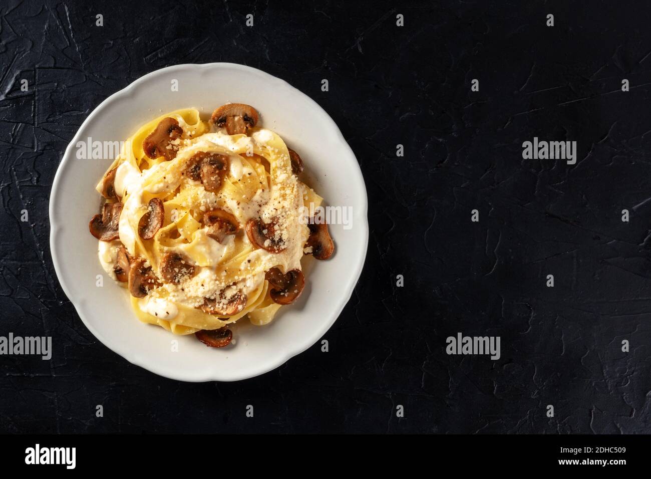 Pasta with mushrooms sauce and grated cheese, shot from athe top on a black background Stock Photo