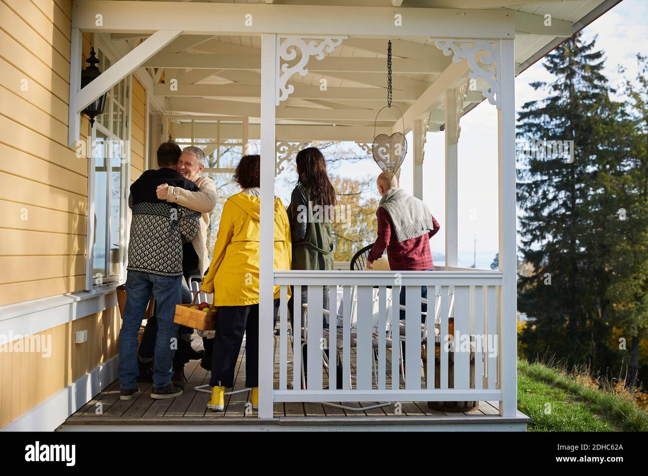 Happy mature men embracing while standing on porch by friends Stock Photo