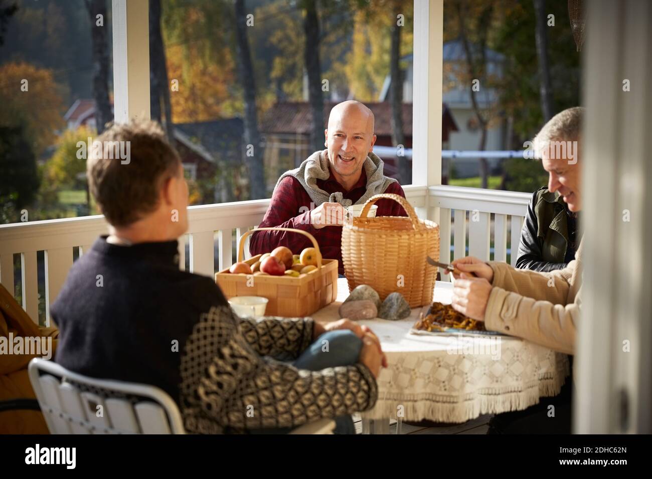 Happy mature men talking while sitting on porch Stock Photo