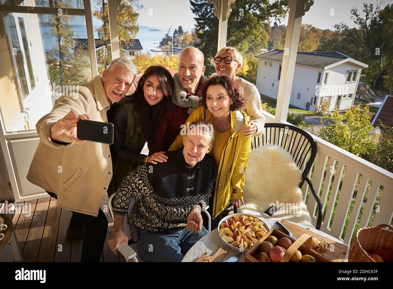 High angle view of happy mature man taking selfie with friends on porch Stock Photo