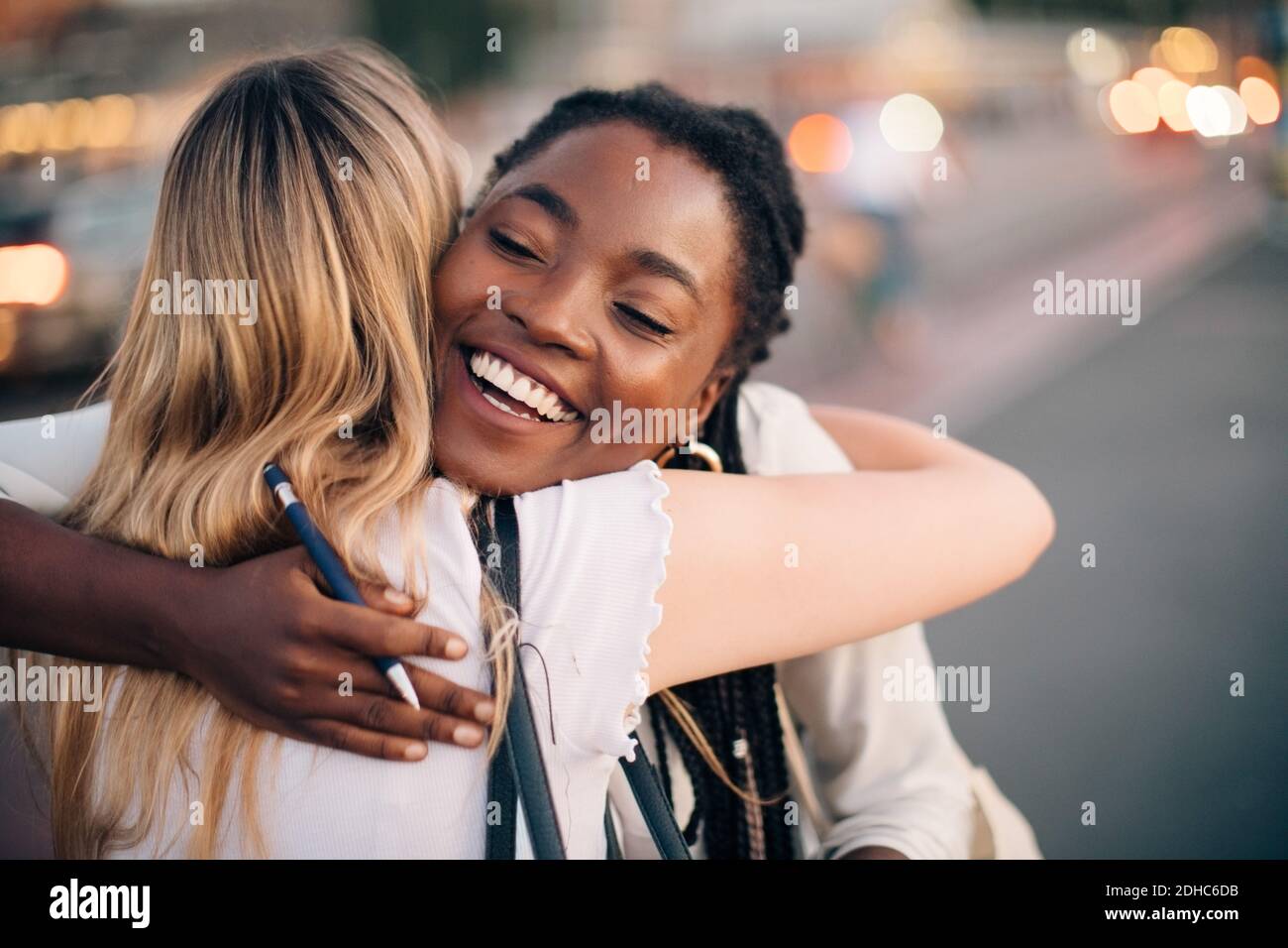 Multi-ethnic female friends embracing each other on street in city Stock Photo