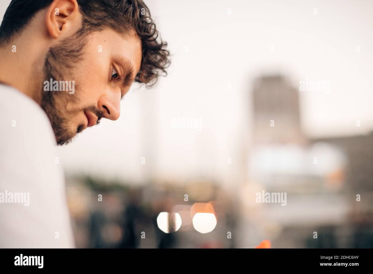 Thoughtful young man looking down during city break Stock Photo