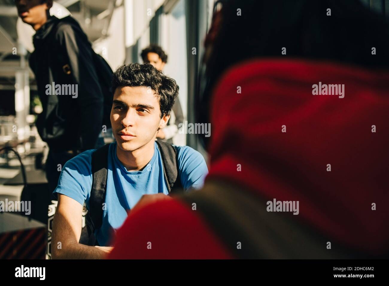 Young man looking away while sitting with friend in restaurant Stock Photo