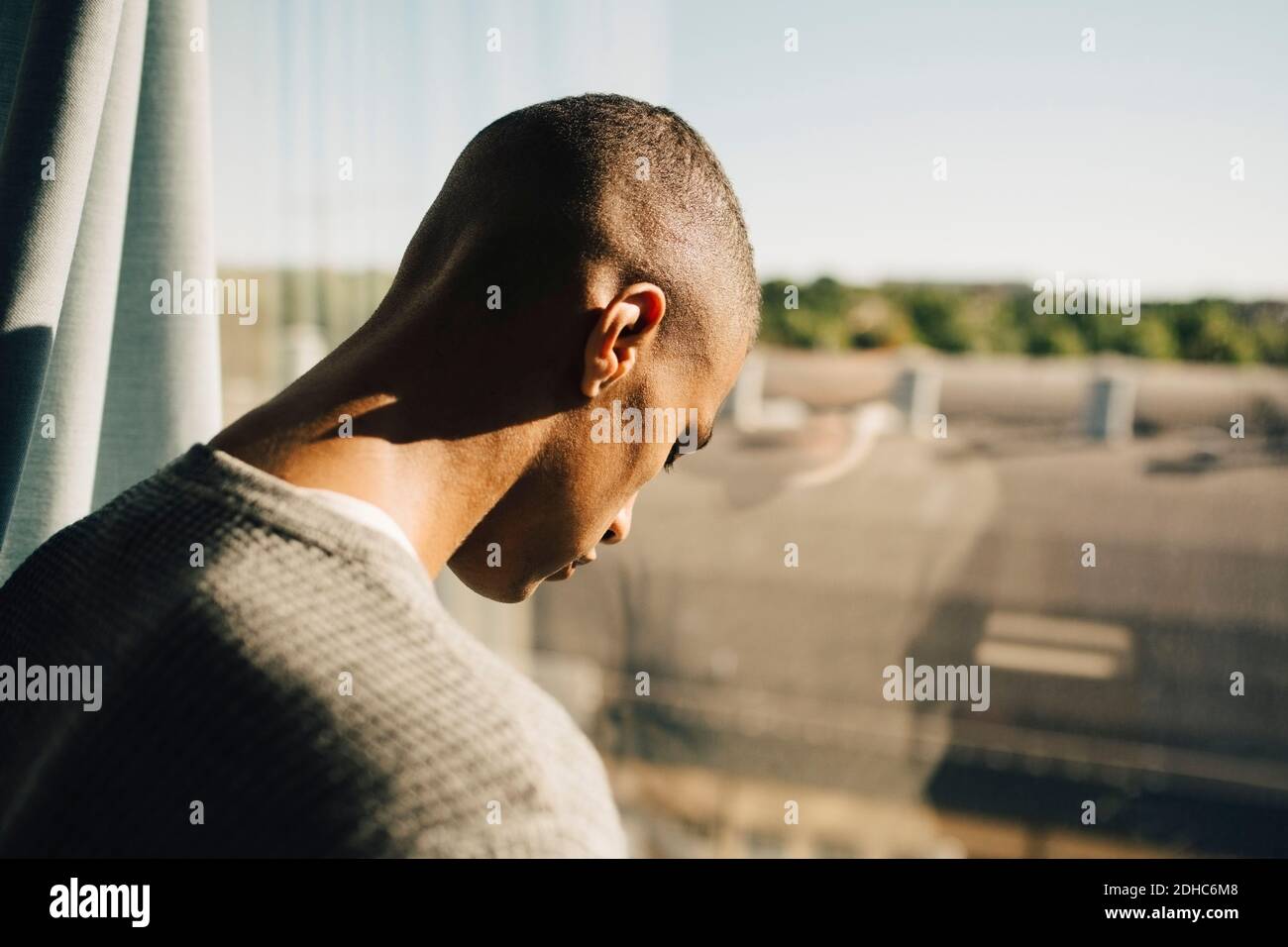 Side view of teenage boy touching glass window with head in restaurant Stock Photo