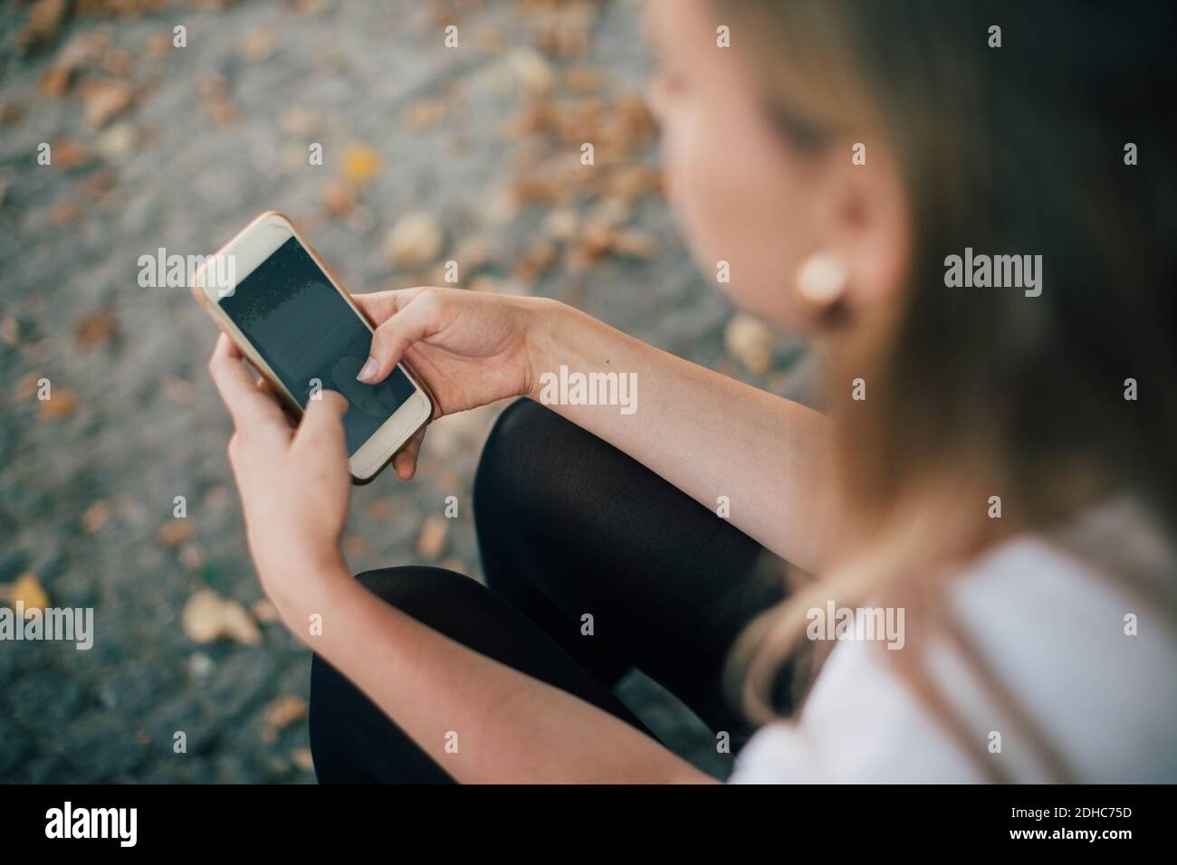 High angle view of young woman using mobile phone while sitting on footpath Stock Photo