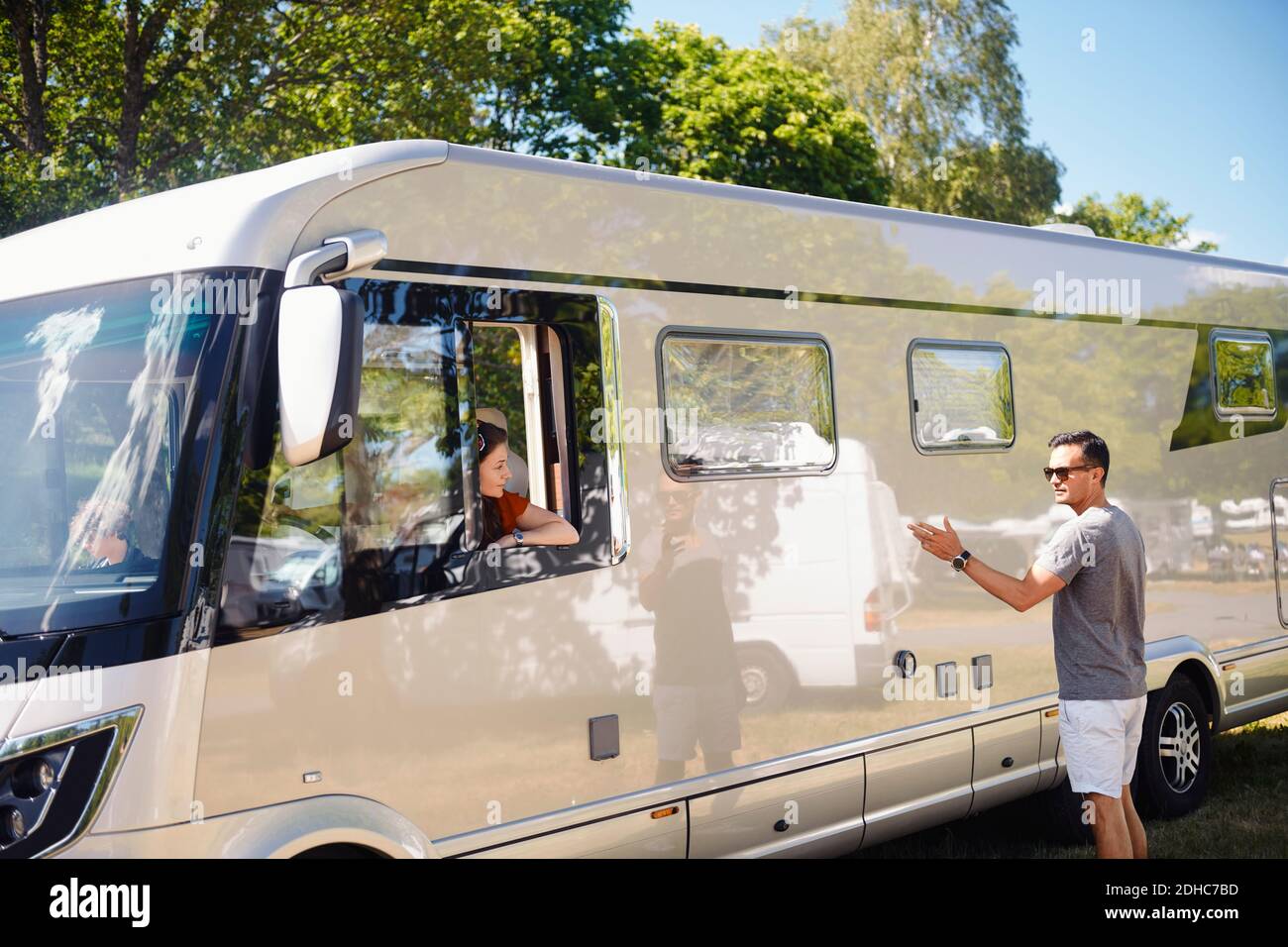 Man talking to woman sitting in motor home during summer vacation Stock Photo