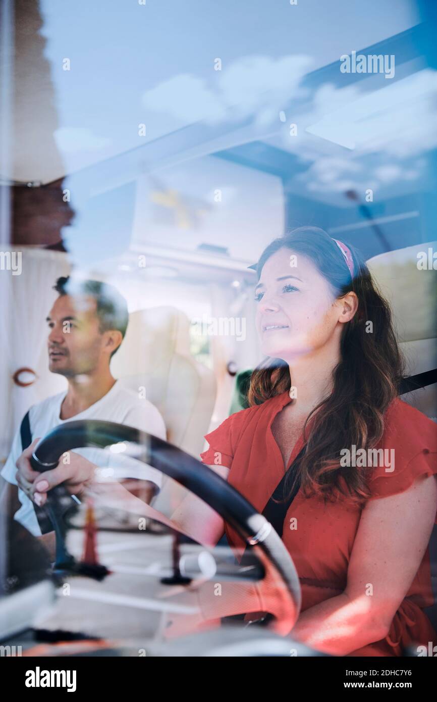 Woman driving van while sitting with man seen through windshield Stock Photo