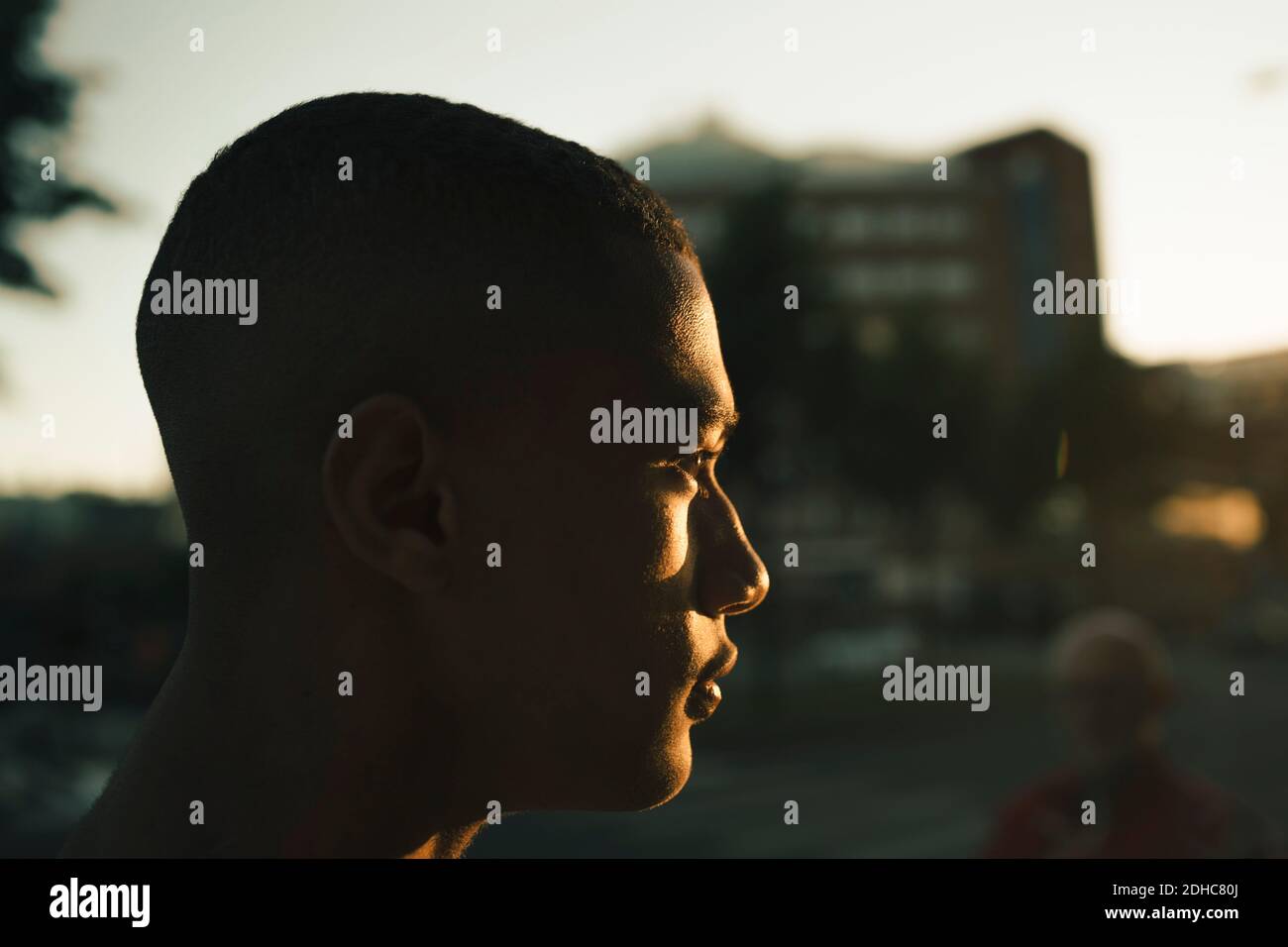 Side view of thoughtful teenage boy looking away in city during sunset Stock Photo