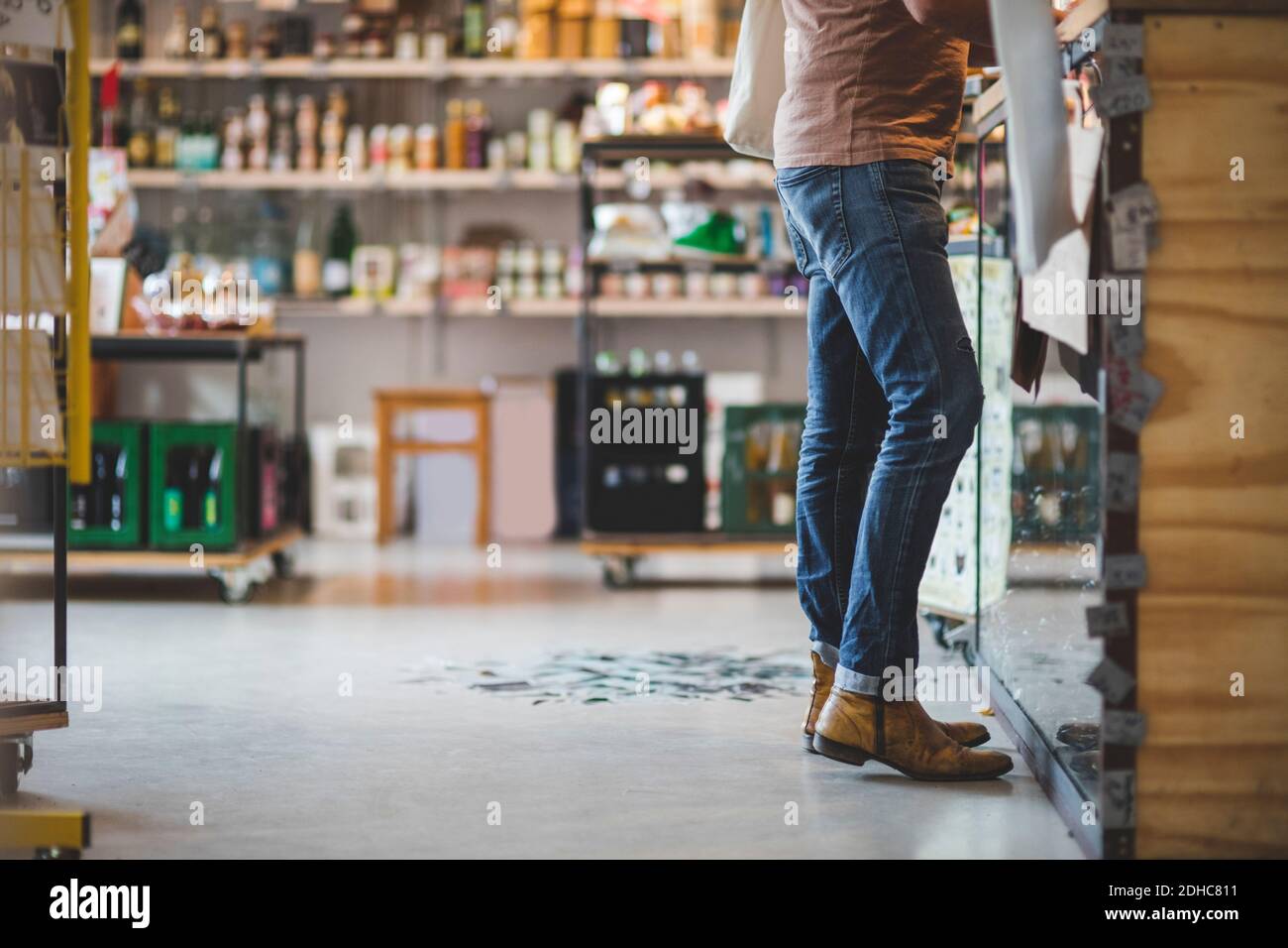 Low section of customer standing at checkout counter in deli Stock Photo