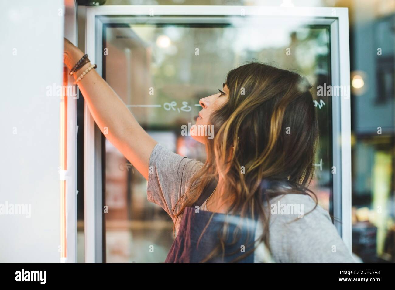 Female employee searching in refrigerator at deli Stock Photo