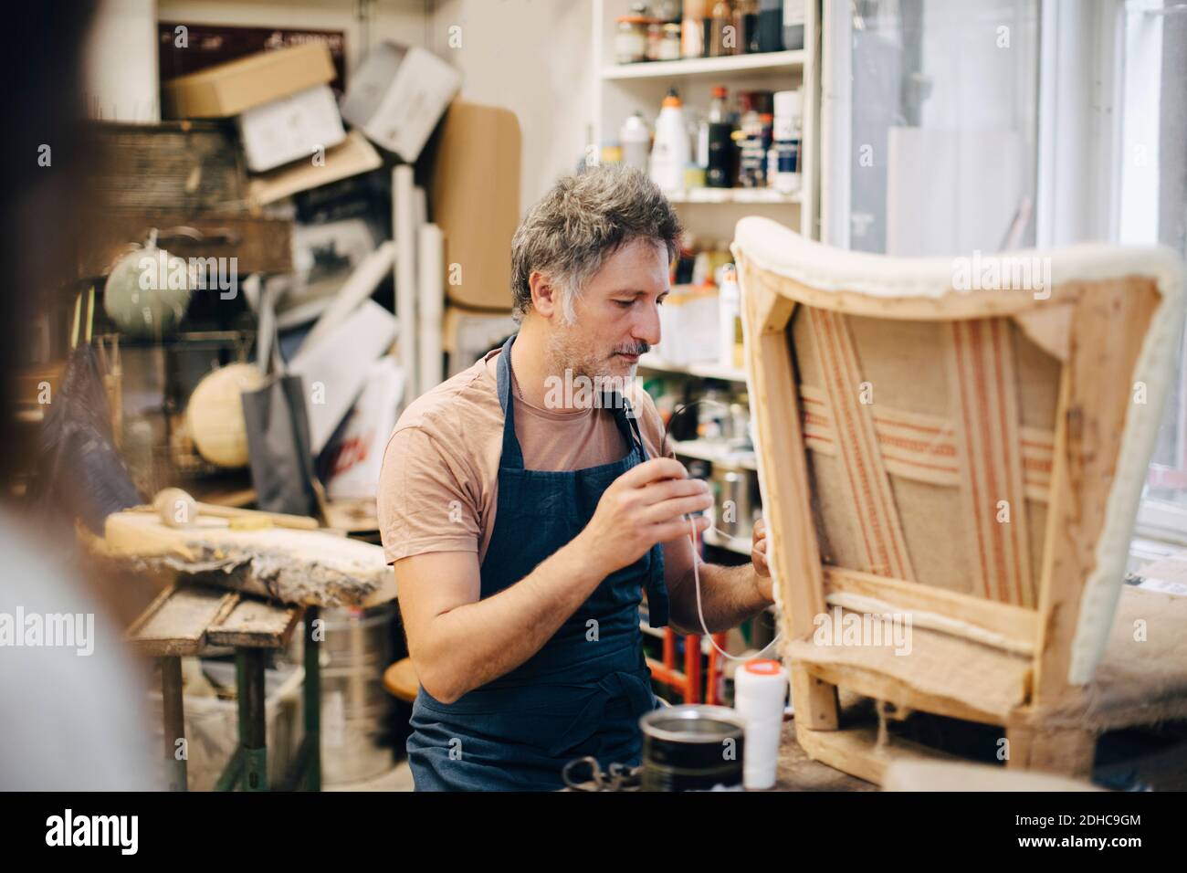 Craftsperson stitching chair in workshop Stock Photo