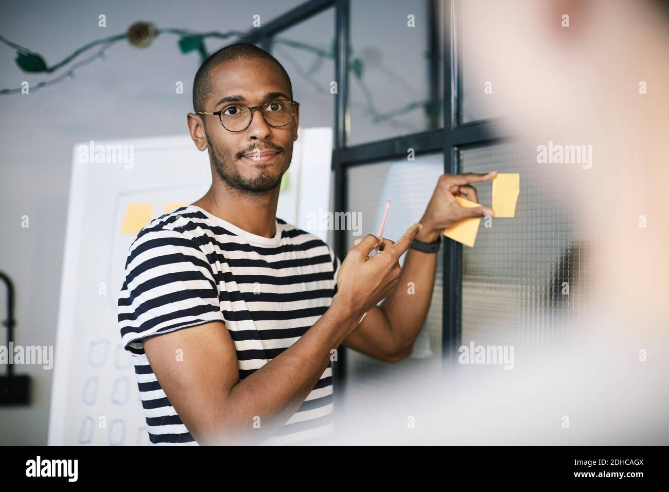 Creative businessman showing adhesive note to colleague in office Stock Photo