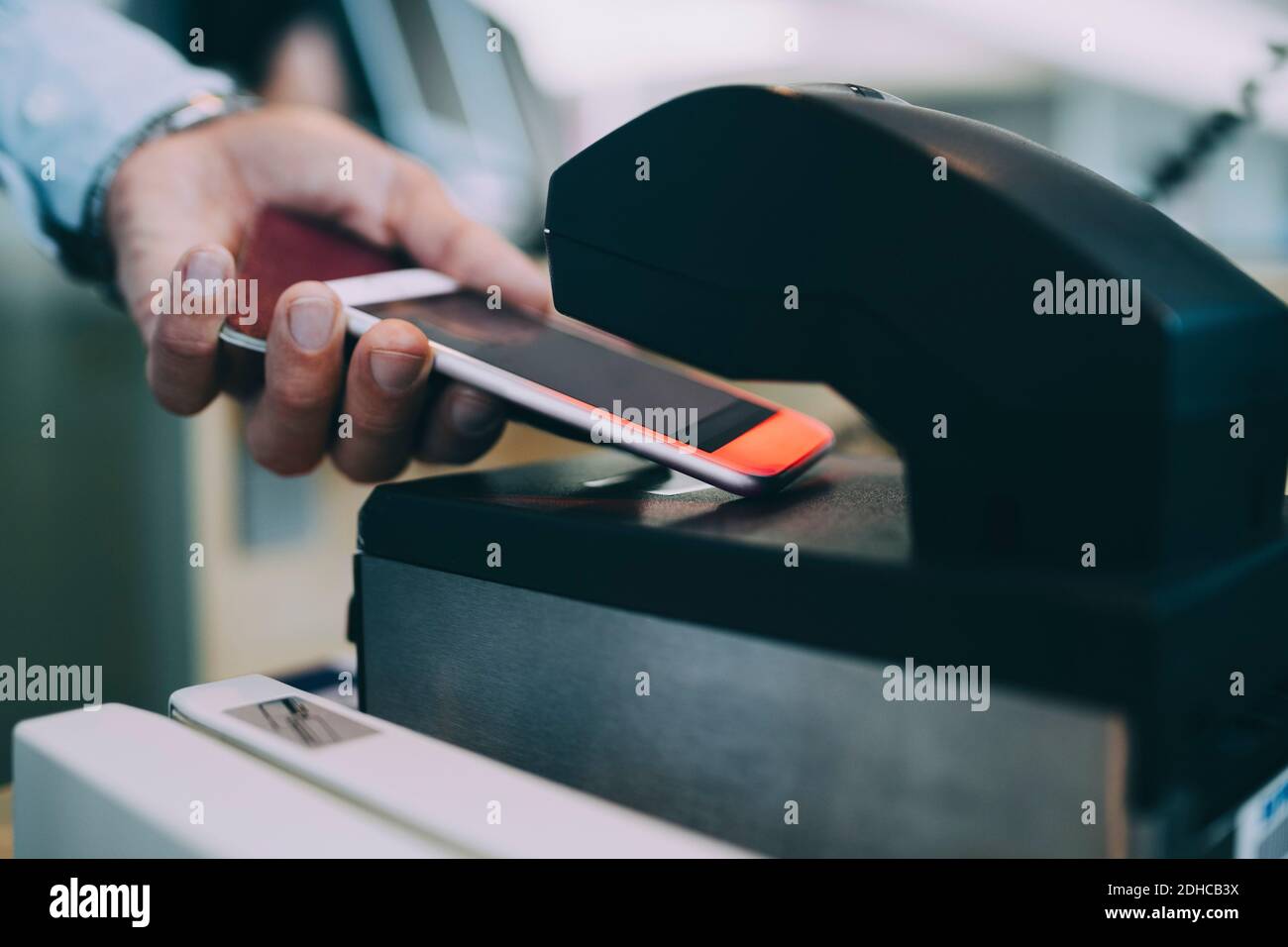 Cropped hands of businessman scanning ticket on smart phone at airport check-in counter Stock Photo